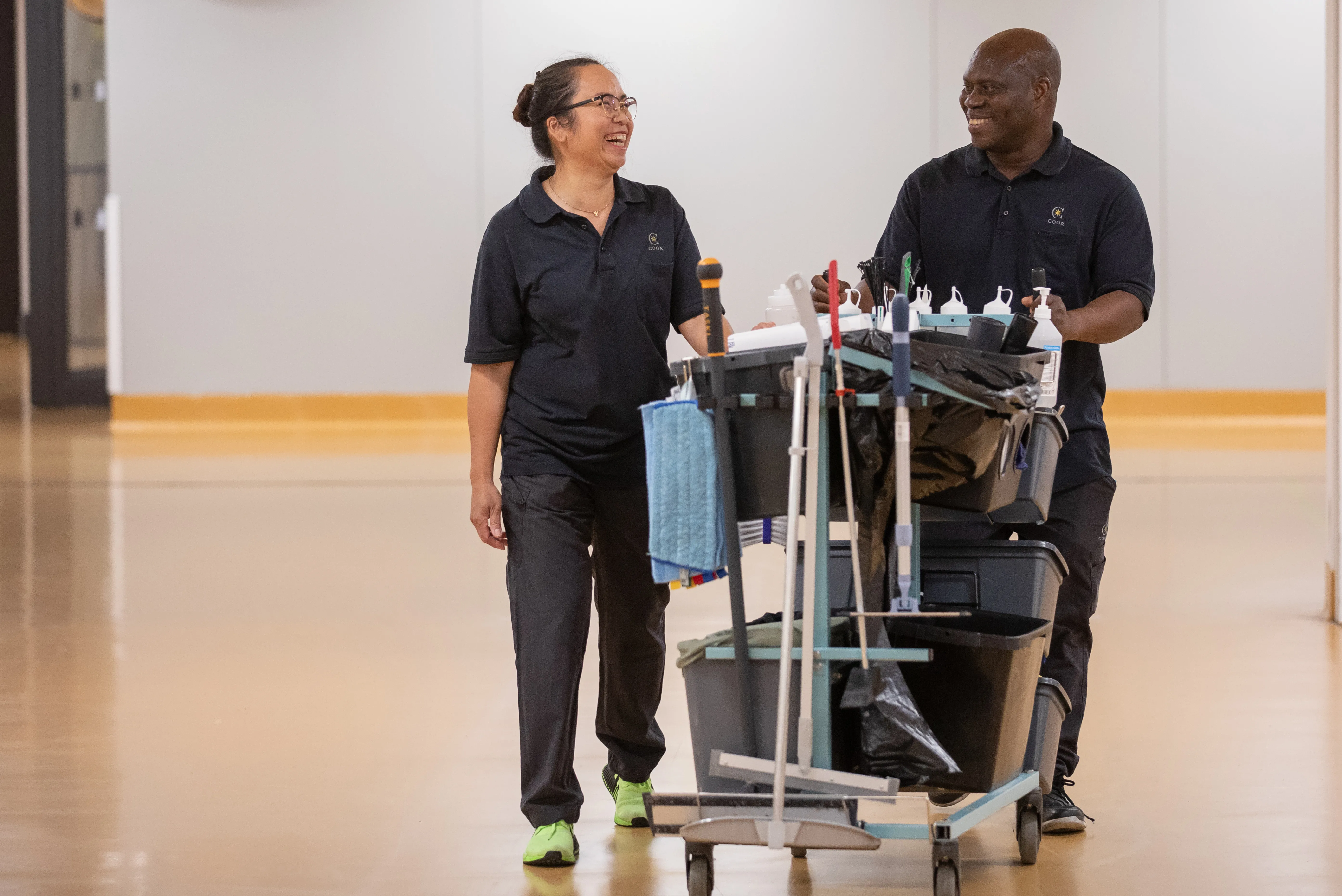 Hymyilevät siivoojat ja siivousvaunu