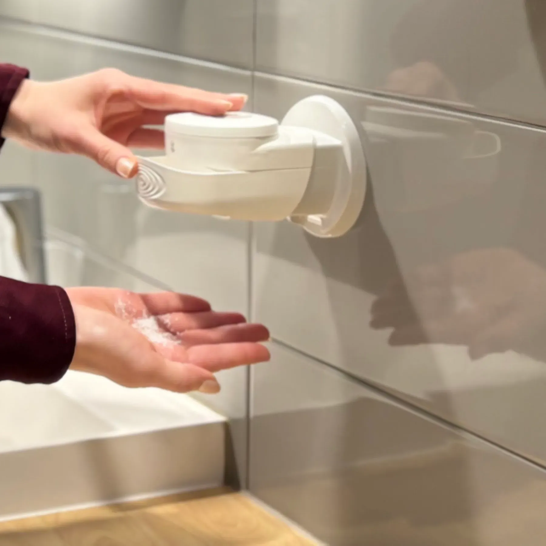 Kädet ottavat palasaippuaa annostelijasta