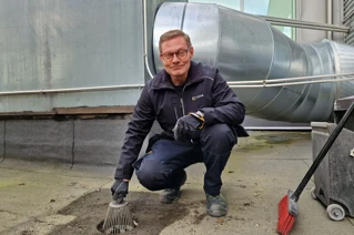 Kiinteistönhoitaja puhdistaa kattokaivoa