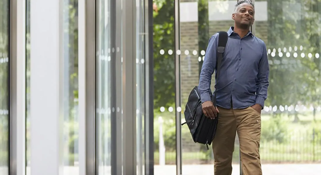 Mies kävelee tietokonelaukku olallaan