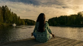 Nainen meditoi järven rannalla