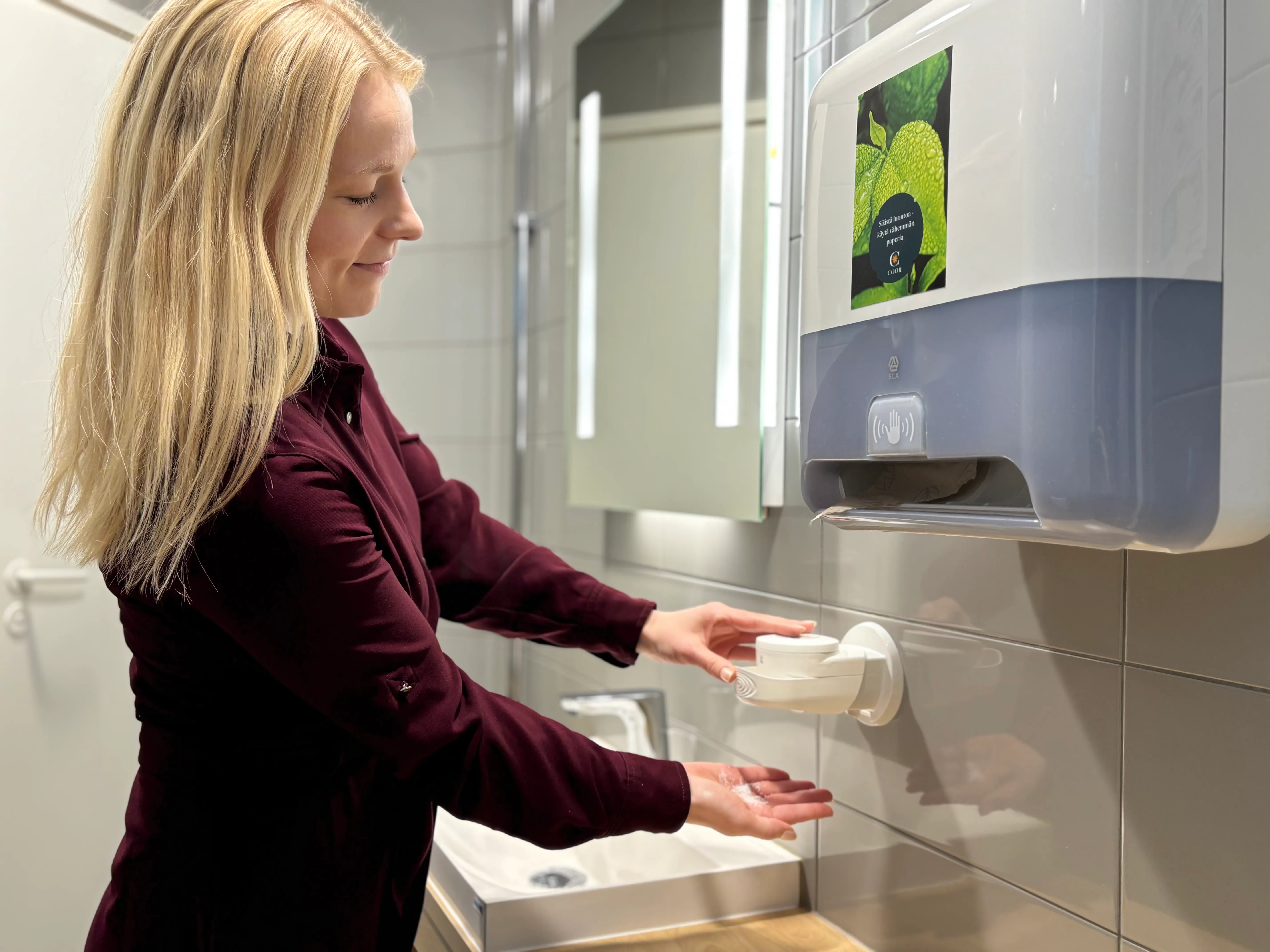 Nainen ottaa annostelijasta saippuaa